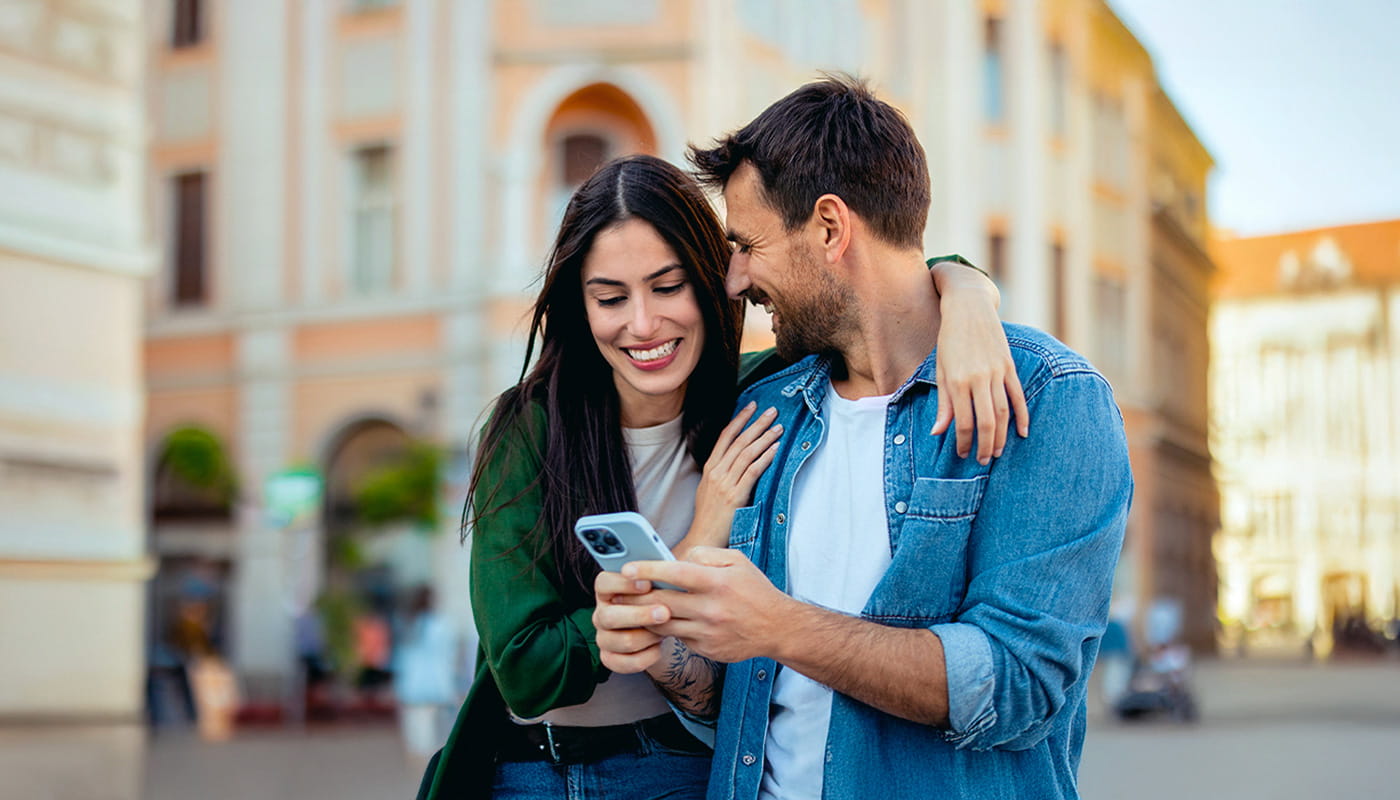 Coppia sorridente che guarda insieme lo schermo di uno smartphone