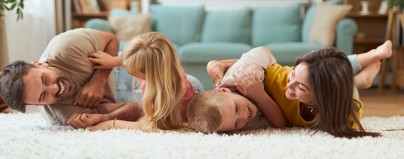 Genitori con figli che giocano sul tappeto di casa